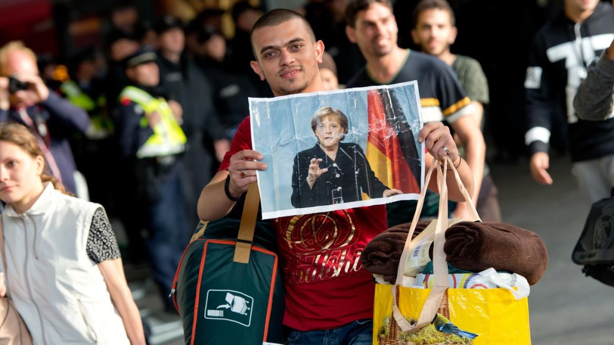Ein Flüchtling, der kurz zuvor mit einem Zug angekommen ist, hält voller Hoffnung ein Foto von Angela Merkel in den Händen.(Archiv)