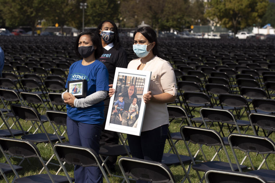 Liza Billing, left, and Naeha Quasba hold photographs of their loved ones, who lost their life due the COVID-19, during the National COVID-19 Remembrance, at The Ellipse outside of the White House, Sunday, Oct. 4, 2020, in Washington. (AP Photo/Jose Luis Magana)