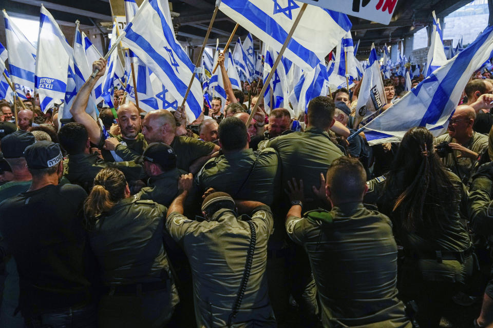 Israeli border police officers disperse demonstrators trying to block the entrance to Israel's main international airport during a protest against plans by Prime Minister Benjamin Netanyahu's government to overhaul the judicial system, at Ben Gurion Airport in Lod, near Tel Aviv, Israel, Monday, July 3, 2023. Thousands of Israelis blocked traffic and snarled movement at the country's main international airport. (AP Photo/Ohad Zwigenberg)