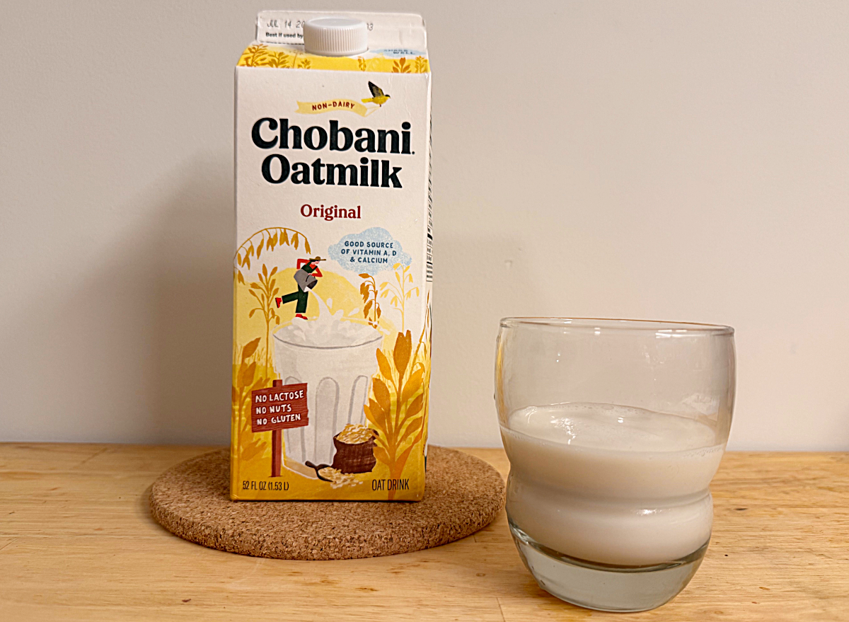 a container of chobani oat milk next to a glass
