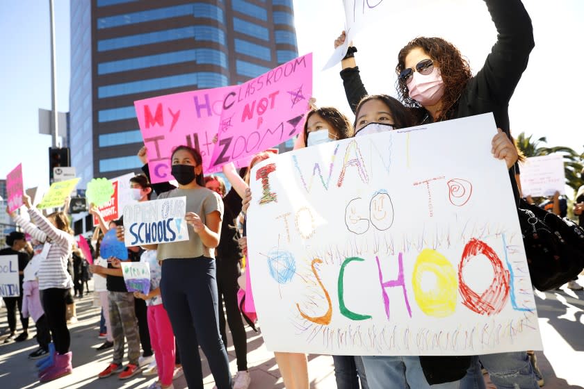 LOS ANGELES-CA-FEBRUARY 22, 2021: Mona Garcia, right, with her daughters Olivia, 8, front, and Maya, 11, of North Hills, participate in a demonstration outside the West L.A. Federal Building to pressure the L.A. Unified School District to bring students back for in-person instruction and other services on Monday, February 22, 2021. (Christina House / Los Angeles Times)