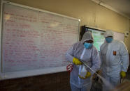 Disinfection team disinfect a classroom at Ivory Park Secondary School east of Johannesburg, South Africa, Thursday, May 28, 2020, ahead of the June 1, 2020, re-opening of Grade 7 and 12 learners to school.(AP Photo/Themba Hadebe)