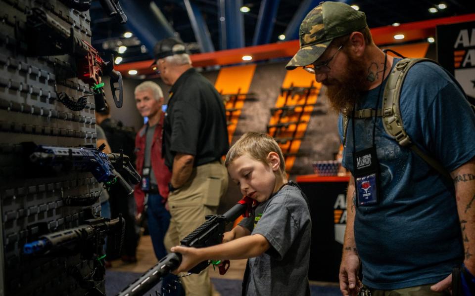 A father oversees his son as he steadies an AR-15 rifle at the NRA convention in Houston - Getty