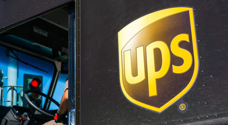 Close up of UPS logo printed on a delivery truck; partial view of the driver sitting at the wheel, waiting at a red traffic light in south San Francisco bay