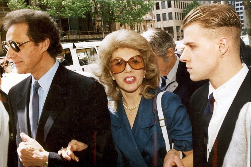 the founder locking arms with two men beside her as they walk outside