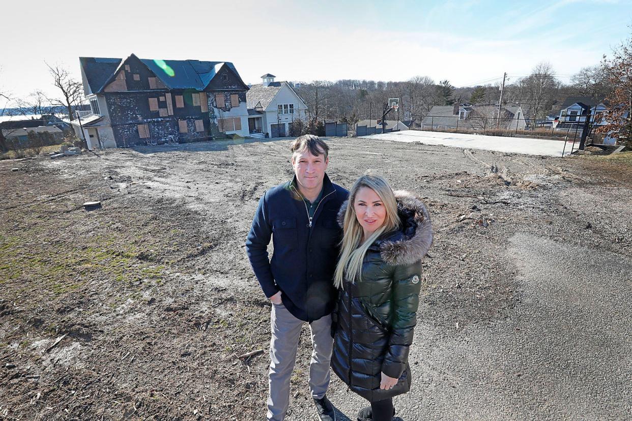 Pat and Haley Cutter stand on the lot their home once occupied on Thursday, Feb. 2, 2023. The home on Mann Street in the Crow Point neighborhood of Hingham burned down last year.