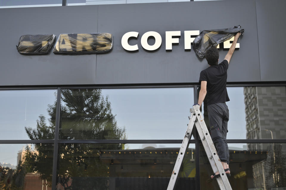 A worker removes a cover from the name of a newly opened Stars Coffee coffee shop in the former location of the Starbucks coffee shop in Moscow, Russia, Thursday, Aug. 18, 2022. A new chain of coffee shops opens Thursday in Moscow, after Russian singer and entrepreneur Timur Yunusov, better known as Timati, together with Russian restaurateur Anton Pinskiy bought the Starbucks stores following company's withdrawal from Russia. (AP Photo/Dmitry Serebryakov)