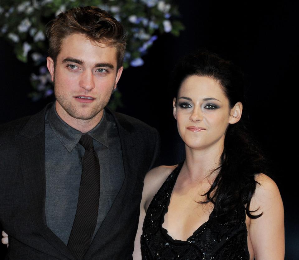 Robert Pattinson, in a gray suit and tie, and Kristen Stewart, in a black halter dress, pose for photos at the 2011 premiere of "Breaking Dawn Part 1."