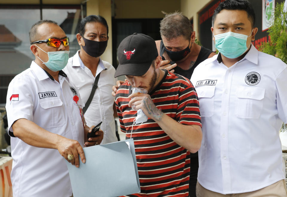 Police officers escort British national Collum Park, center, and Australian national Aaron Wayne Coyle, rear, at the regional police headquarters in Denpasar, Indonesia on Thursday, Sept. 3, 2020. Indonesian police say the men have been arrested with methamphetamine and ecstasy drugs on the tourist island of Bali. (AP Photo/Firdia Lisnawati)