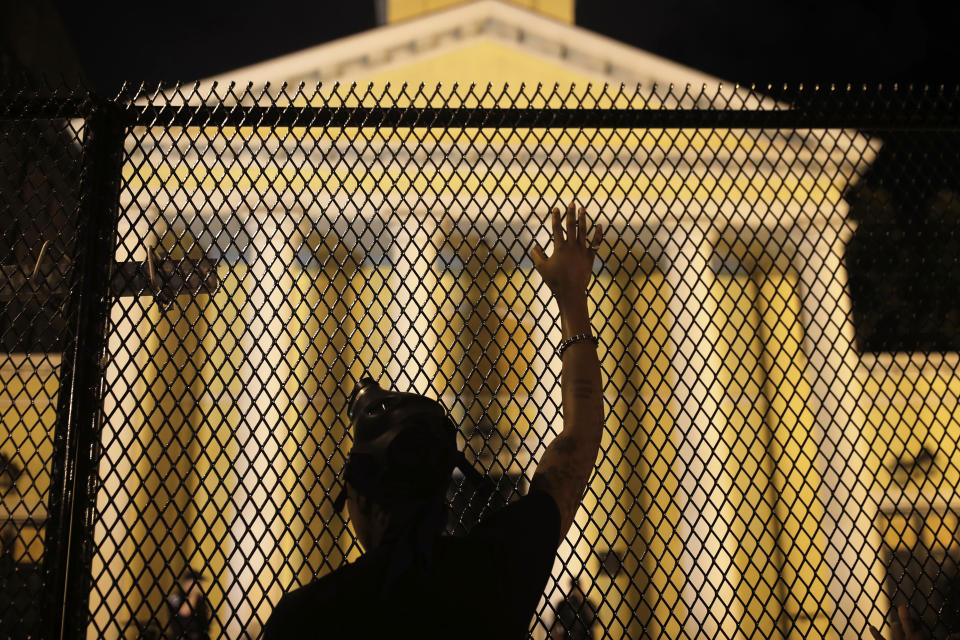 FILE - In this early Wednesday, June 24, 2020 file photo, a protester calls out to police standing guard behind security fencing at St. John's Episcopal Church, near the White House, amid continuing anti-racism demonstrations following the death of George Floyd, a Black man who died while being restrained by police in Minneapolis. St. John's, at the epicenter of protests in Washington, has a long legacy on civil rights dating to its embrace of the 1963 March on Washington. (AP Photo/Maya Alleruzzo)