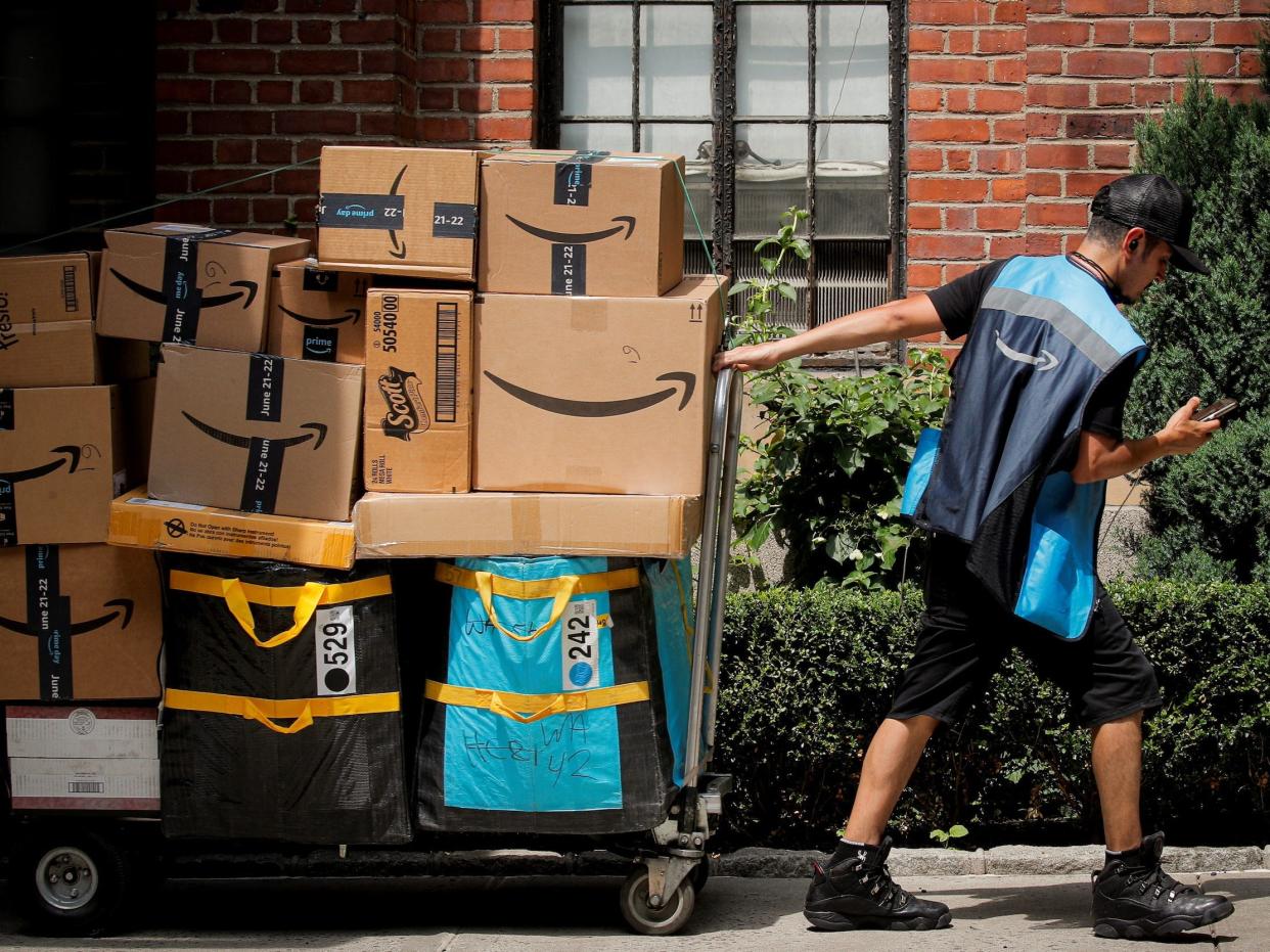 An Amazon delivery worker pulls a delivery cart full of packages during its annual Prime Day promotion in New York