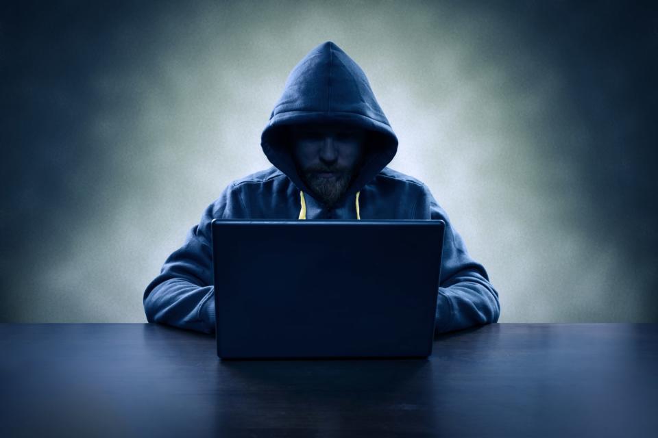 Computer hacker stealing information with laptop