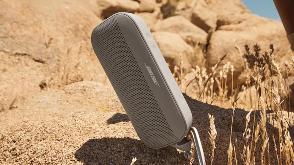 The gravity-defying Bose SoundLink Flex sits in a corner facing the desert brush on the rocky hills. Product life promotion image.