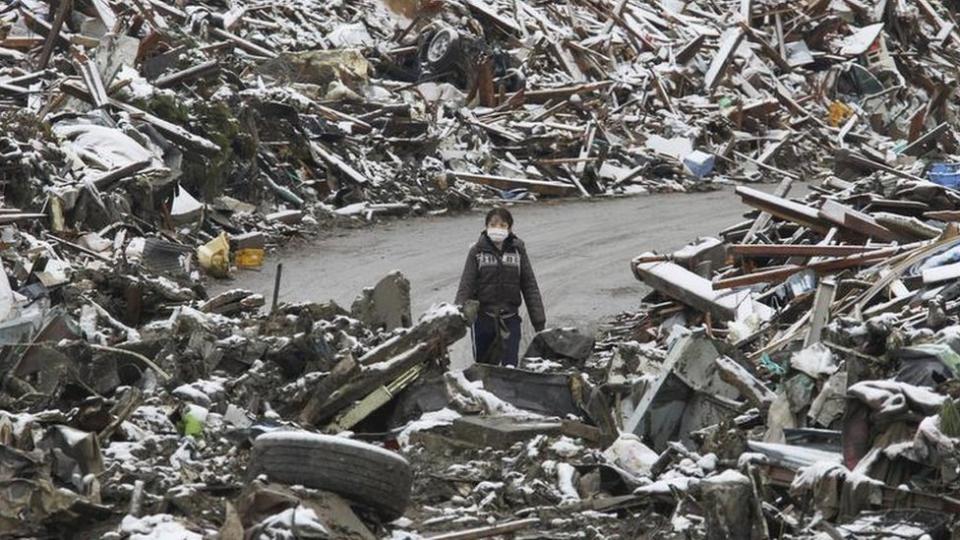 Un mujer camina entre los escombros en el pueblo japonés Minamisanriku, en el norte de Japón, tras el tsunami de 2011.