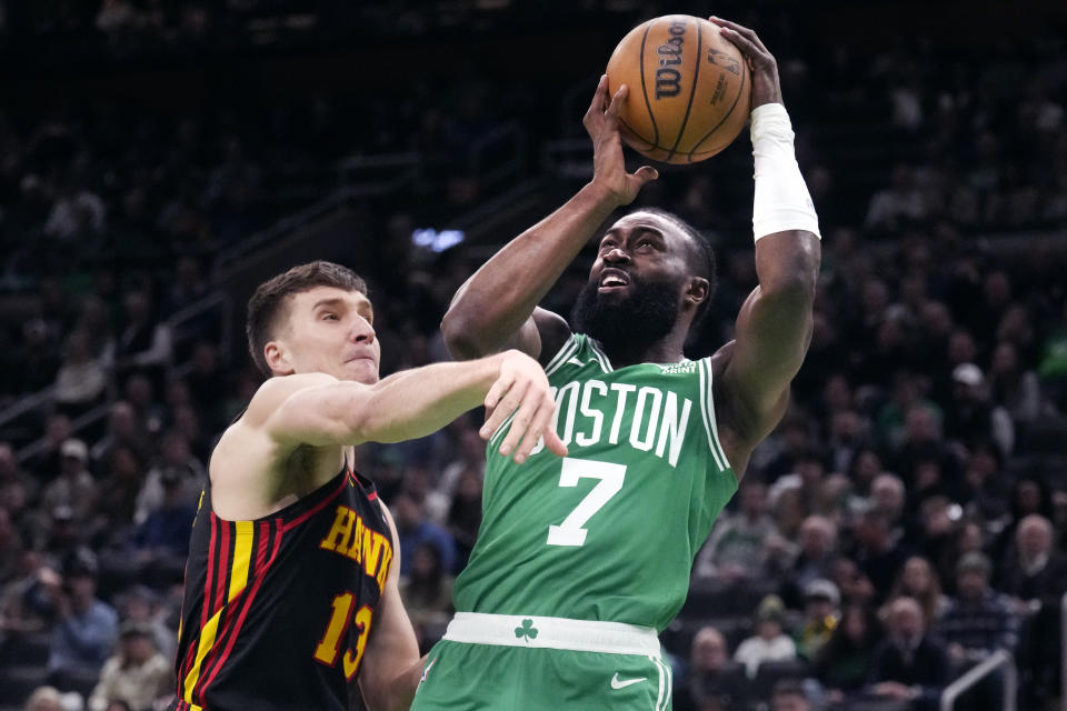 Boston Celtics guard Jaylen Brown (7) shoots while pressured by Atlanta Hawks guard Bogdan Bogdanovic (13) during the first half of an NBA basketball game Wednesday, Feb. 7, 2024, in Boston. (AP Photo/Charles Krupa)