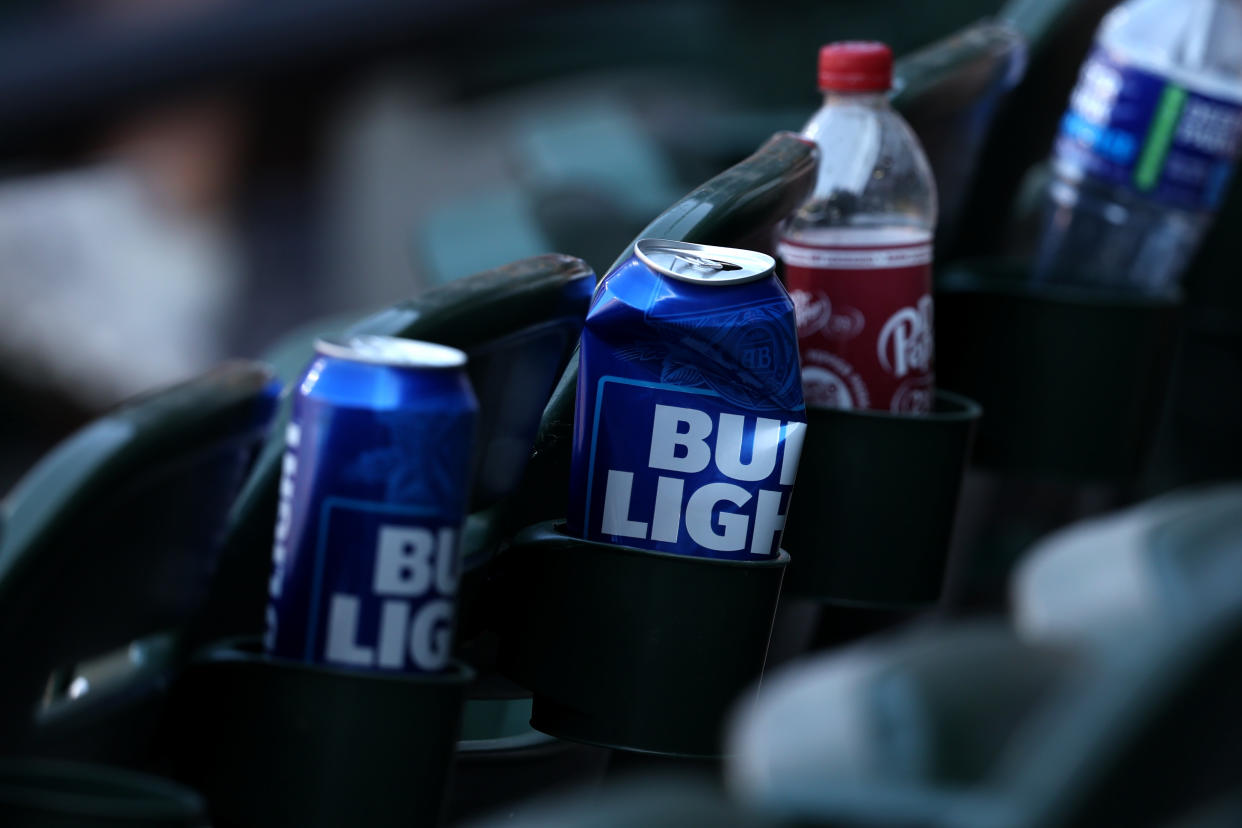Empty Bud Light cans sit in the seats at a baseball game.