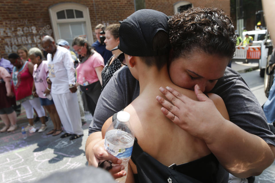 A couple embrace as they participate in prayers at the intersection where Heather Heyer was killed last year as they mark the anniversary of the Unite the Right rally in Charlottesville, Va., Sunday, Aug. 12, 2018. On that day, white supremacists and counterprotesters clashed in the city streets before a car driven into a crowd struck and killed Heyer. (AP Photo/Steve Helber)