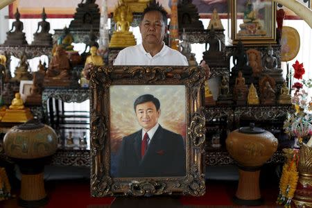 Red shirt movement leader Kwanchai Praipana poses with a photo of former PM Thaksin Shinawatra at his office in Udon Thani, Thailand, September 15, 2015. REUTERS/Jorge Silva