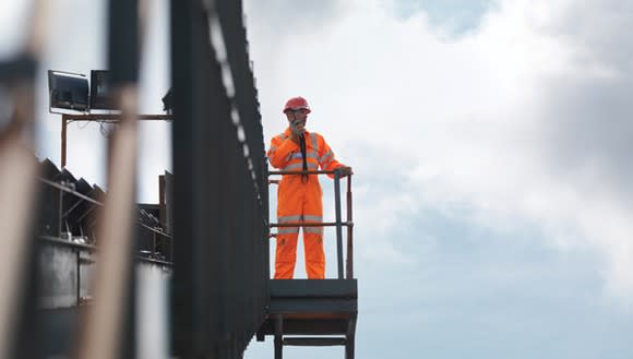 A man in an orange jumpsuit and hardhat at a launch site.