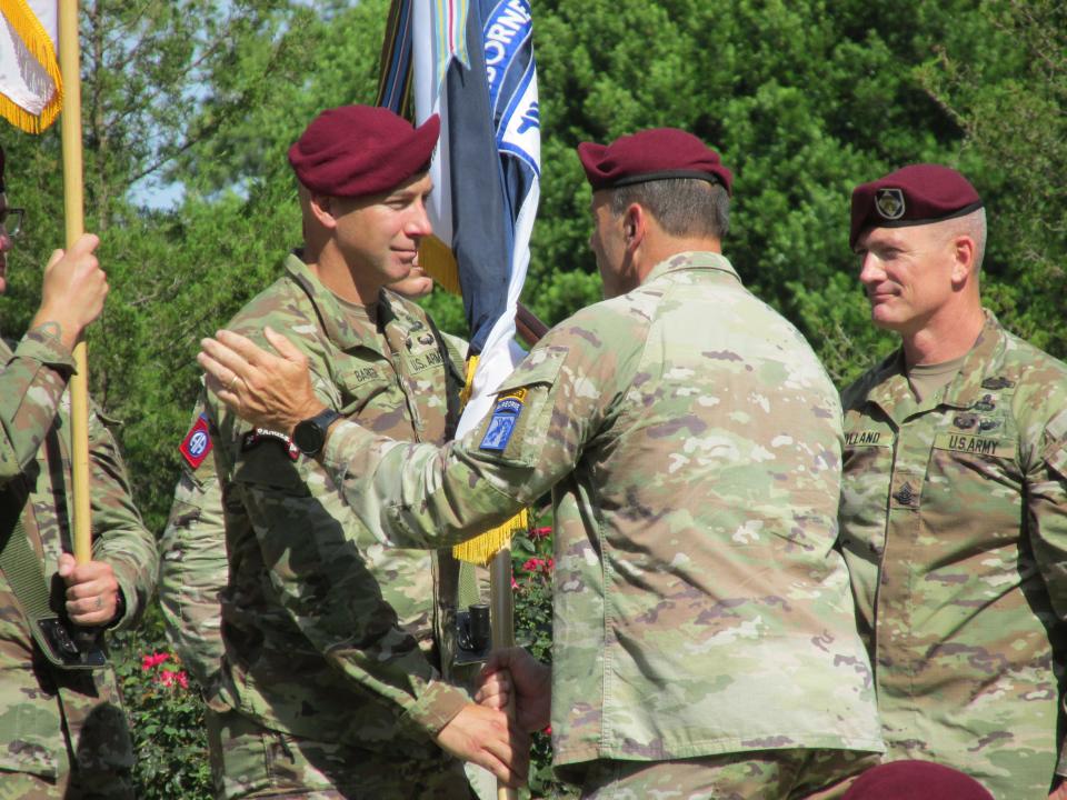 Lt. Gen. Christopher Donahue, commander of the 18th Airborne Corps, passes the unit colors to incoming Command Sgt. Maj. Bryan Barker, while outgoing Command Sgt. Maj. T.J. Holland looks on during a change of responsibility ceremony Friday, Aug. 11, 2023, on Fort Liberty.