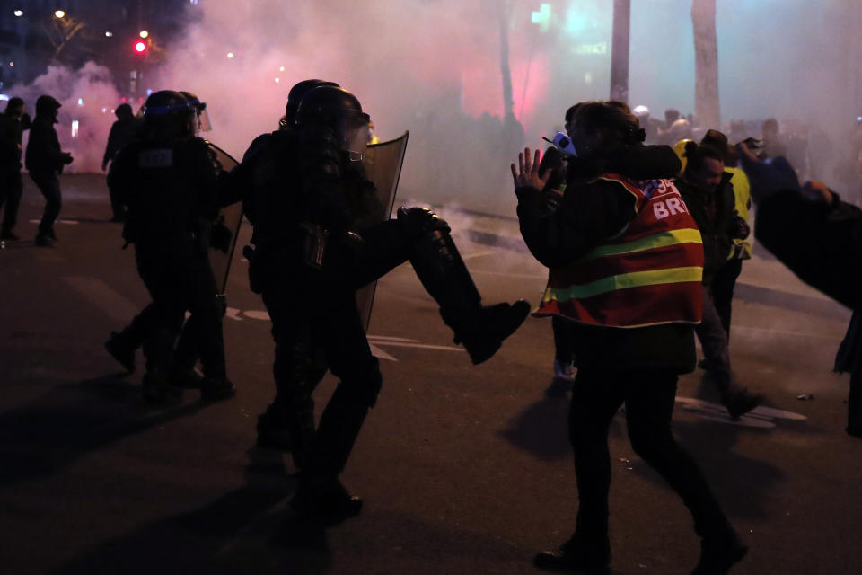 French riot officers kick a woman during a demonstration, Saturday, Jan. 11, 2020 in Paris. The French government and labor unions appeared far from reaching any compromise deal Friday in talks over a planned pension overhaul, with strikes and protests grinding on. (AP Photo/Francois Mori)