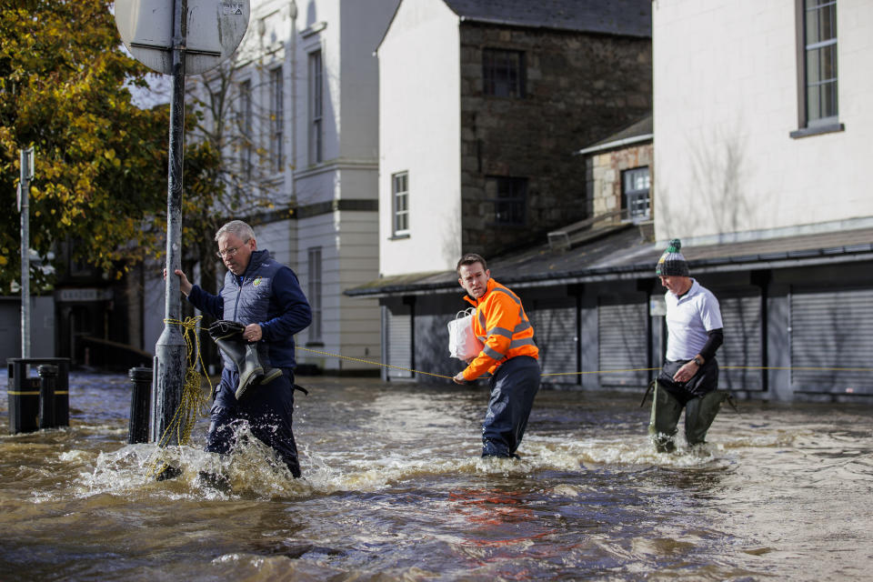 People walk through flood water on Bank Parade in Newry Town, Co Down, Northern Ireland, Tuesday, Oct. 31, 2023. Flooding was reported in parts of Northern Ireland, with police cautioning people against travelling due to an amber rain warning. (Liam McBurney/PA via AP)