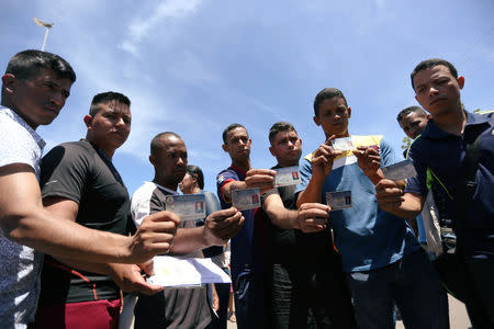 Members of Venezuela's National Guard Luis Eduardo Gonzales Laya, Jose Antonio Moreno Penazola, Orlando Abimelec Villazana Arevalo, Jorge Luis Gonzalez Romero, Jose Alexander Sanguino Escalante, Jean Carlos Cesar Parra and Carlos Eduardo Zapata who defected to Brazil show their military IDs near the border in Pacaraima, Brazil February 25, 2019. REUTERS/Bruno Kelly