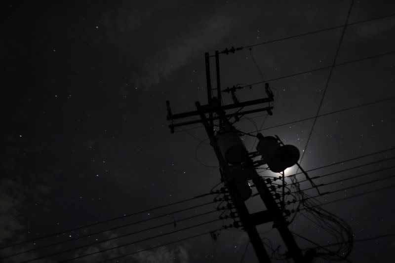 An electricity tower is seen against moonlight during a blackout in Guigue