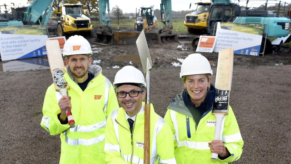 Officials pose with diggers, cricket bats and spade