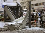 People walk past a ruined bus stop which was crushed by part of fallen outer wall of a nearby building in Sendai, Miyagi Prefecture (state) after Japan was struck by a strong earthquake off its northeastern coast Friday, March 11, 2011. (AP Photo/Kyodo News)