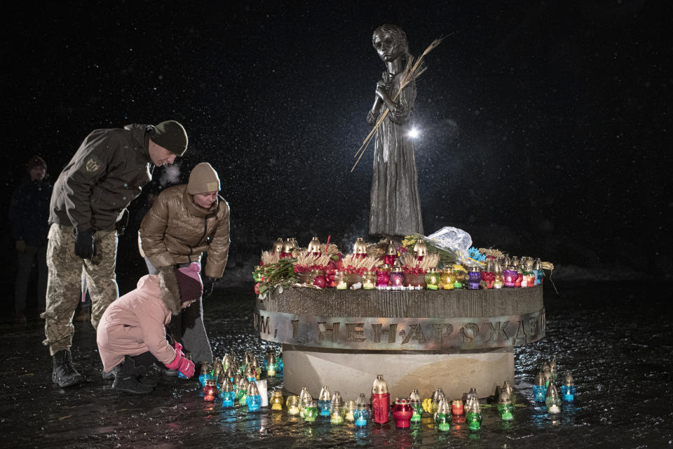 People light candles and lay flowers at the monument of the victims of the Holodomor, Great Famine, which took place in the 1930's and that killed millions, in Kyiv, Ukraine, Saturday, Nov. 26, 2022. (AP Photo/Andrew Kravchenko)