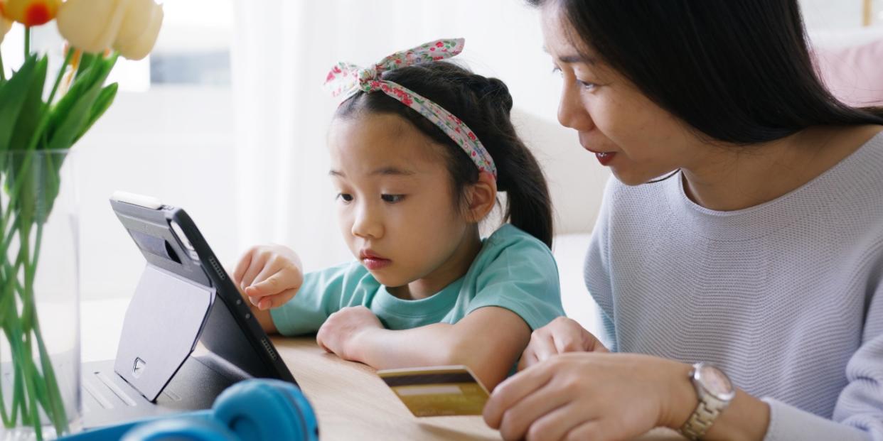 woman teaching chilld about money - mom and child looking at a tablet/ipad