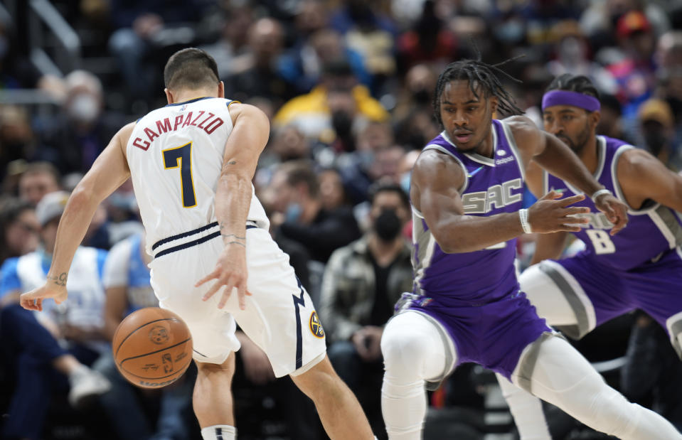 Denver Nuggets guard Facundo Campazzo, left, tries to retrieve the ball as Sacramento Kings guard Davion Mitchell defends during the first half of an NBA basketball game Friday, Jan. 7, 2022, in Denver. (AP Photo/David Zalubowski)