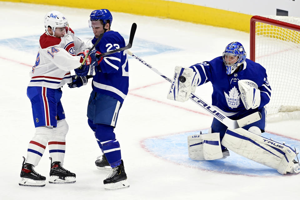 Montreal Canadiens center Nick Suzuki (14) and Toronto Maple Leafs defenseman Travis Dermott (23) clash as Maple Leafs goaltender Frederik Andersen (31) makes a save during the first period of an NHL hockey game in Toronto, Wednesday, Jan. 13, 2021. (Frank Gunn/The Canadian Press via AP)