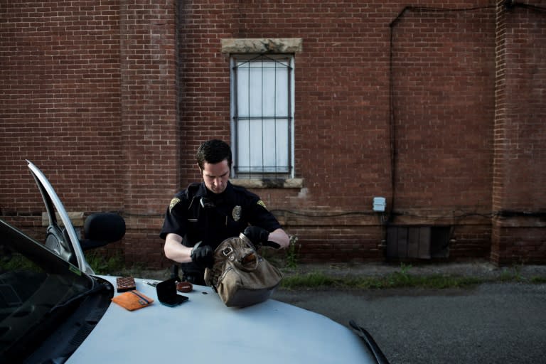 Police officer searches the purse of a suspected prostitute in Huntington, West Virginia, a place where those looking for hope leave and those without turn to drugs