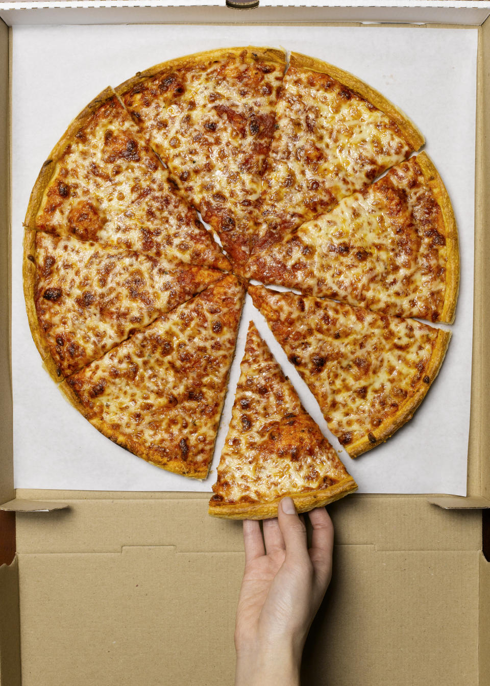 A person removing a slice of pizza from a large pie