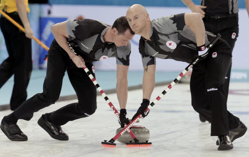 Canada's second E. J. Harnden (L) and vice Ryan Fry sweep ahead of a stone ahead of their men's curling semifinal game against Britain at the 2014 Sochi Olympics in the Ice Cube Curling Center in Sochi February 19, 2014. REUTERS/Ints Kalnins (RUSSIA - Tags: OLYMPICS SPORT CURLING)