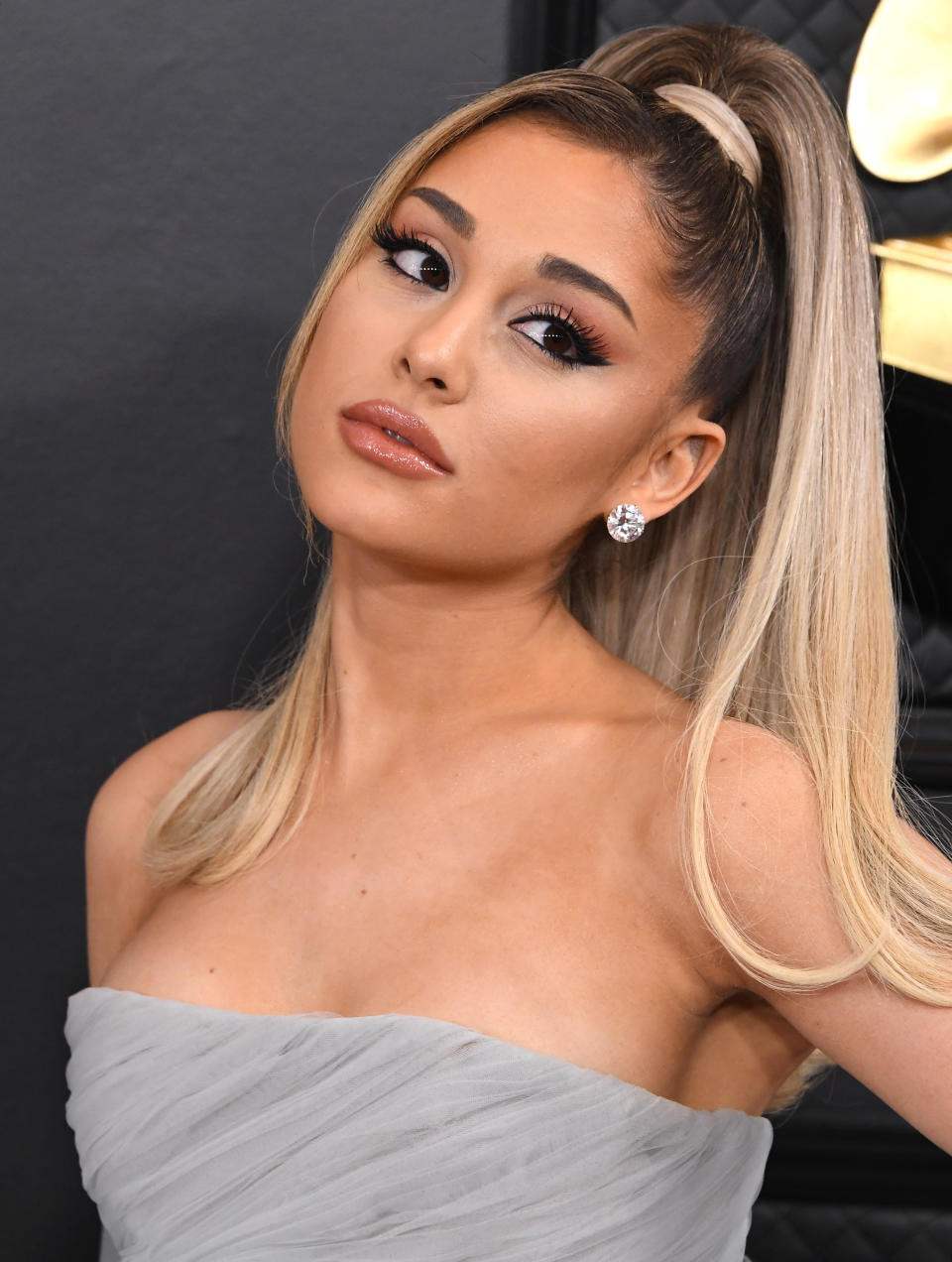 Ariana Grande poses on the red carpet in a strapless dress with a high ponytail and diamond earrings