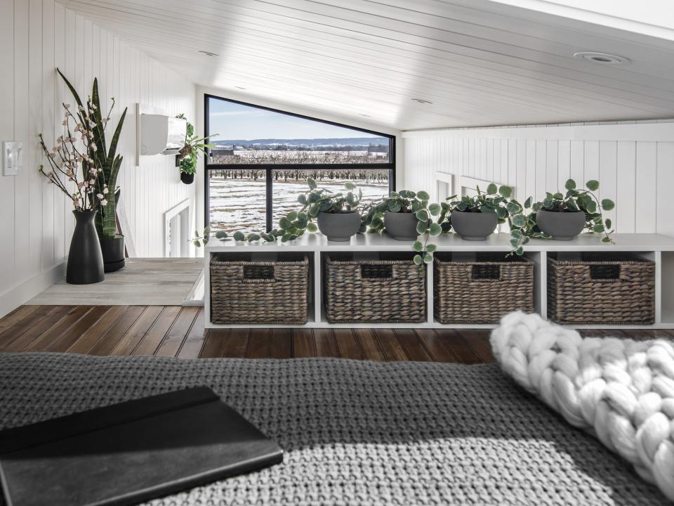 a lofted bedroom with grey storage units on the ground next to the bed