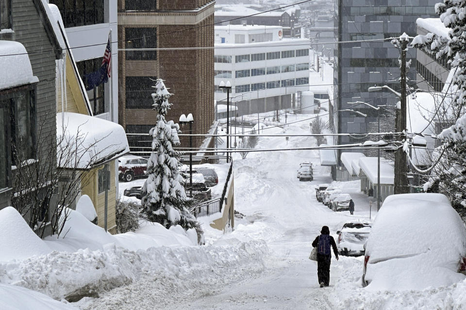 FILE - A pedestrian walks down a steep downtown street in Juneau, Alaska, on Tuesday, Jan. 23, 2024. Much of Alaska has plunged into a deep freeze, with temperatures well below zero and Anchorage seeing some of its coldest temperatures in years as the mayor of the state’s largest city opened warming facilities for those who are homeless or who don't have reliable heating. (AP Photo/Becky Bohrer, File)