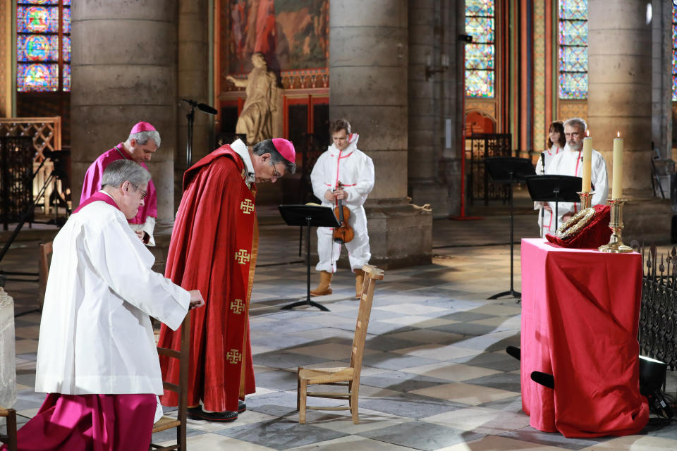 Notre-Dame de Paris cathedral's rector Patrick Chauvet, left, Auxiliary Bishop of Paris Denis Jachiet and Archbishop of Paris Michel Aupetit, third left, violonist Renaud Capucon, actor Judith Chemla and actor Philippe Torreton, right, attend a ceremony to celebrate Good Friday in a secured part of Notre-Dame de Paris cathedral Friday, April 10, 2020, in Paris. Although still damaged and scarred by fire, Notre Dame Cathedral has — if only for an instant — come back to life as a center for prayer in a Paris locked down against the coronavirus. The new coronavirus causes mild or moderate symptoms for most people, but for some, especially older adults and people with existing health problems, it can cause more severe illness or death.(Ludovic Marin, Pool via AP)