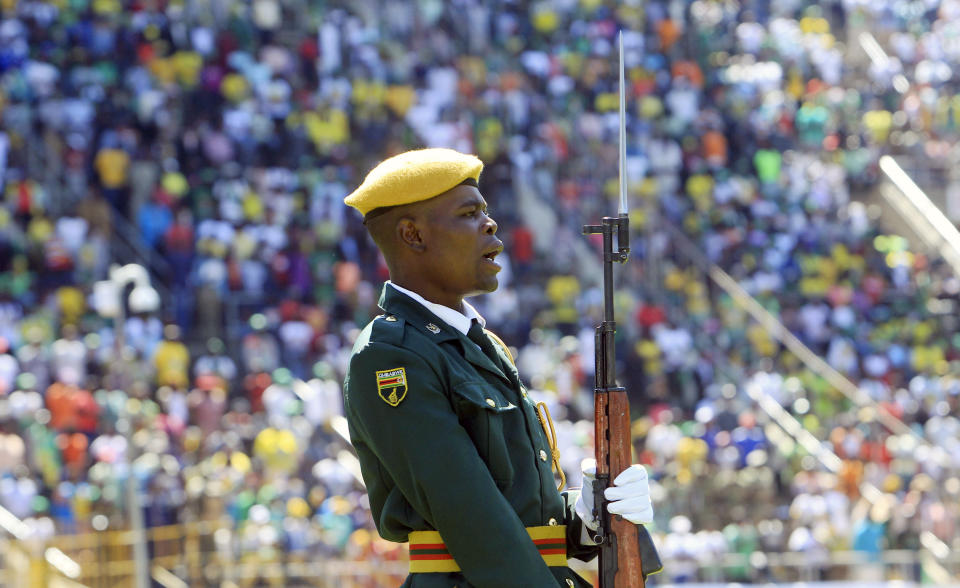 A soldier sings the national anthem, backdropped by crowds of onlookers during Zimbabwean President Emmerson Mnangagwa's inauguration ceremony at the National Sports Stadium in Harare, Sunday, Aug. 26, 2018. The Constitutional Court upheld Mnangagwa's narrow election win Friday, saying the opposition did not provide " sufficient and credible evidence" to back vote- rigging claims.(AP Photo/Tsvangirayi Mukwazhi)