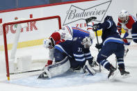 Winnipeg Jets goaltender Connor Hellebuyck (37) makes a save as Montreal Canadiens' Phillip Danault (24) crashes into him during the second period of an NHL hockey game Saturday, Feb. 27, 2021, in Winnipeg, Manitoba. (John Woods/The Canadian Press via AP)