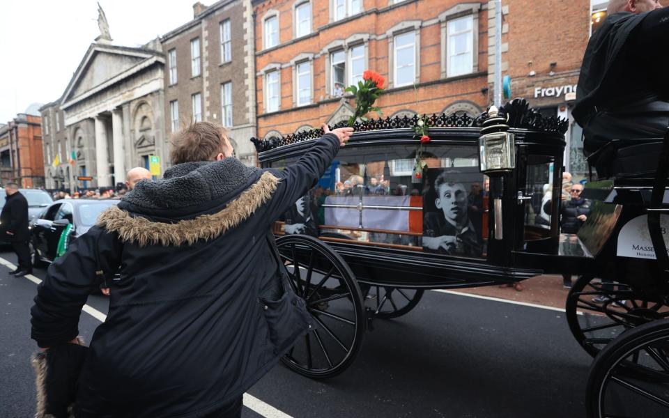 Flowers are thrown at the hearse as Shane MacGowan's funeral procession makes its way through the streets of Dublin