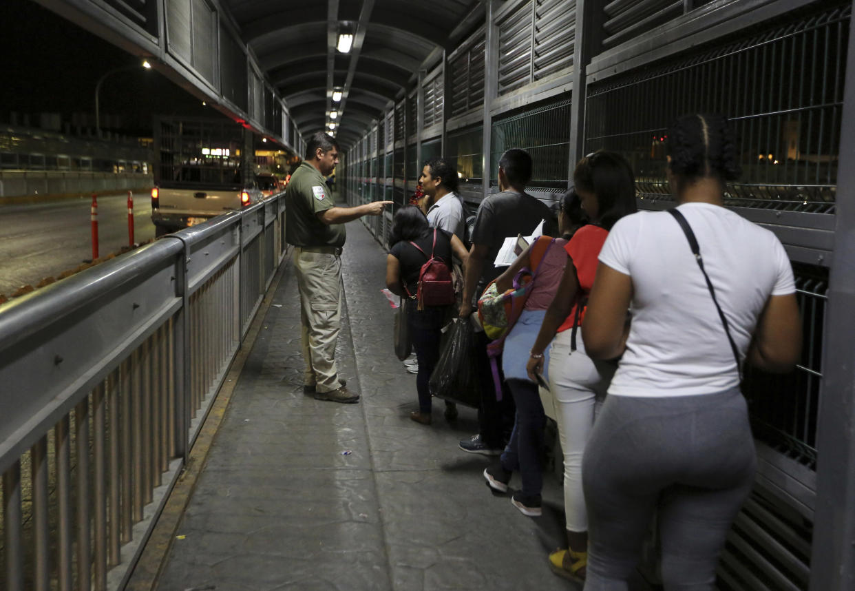 A Mexican immigration officer gives instructions to migrants who are applying for asylum in U.S. as they wait on International Bridge 1 as they prepare to leave Nuevo Laredo, Mexico, and enter Laredo, Texas, early Tuesday, Sept. 17, 2019. (Photo: Fernando Llano/AP)