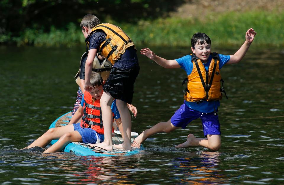 Henry Nagel leaps from a paddle board he was sharing with friends Ben Martin, Connor Dawsey and William Walton during a PARA Outdoor Adventure Camp outing to kayak and paddle board on Lake Nicol Tuesday, July 3, 2018. [Staff Photo/Gary Cosby Jr.]