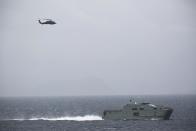 In this Tuesday, March 21, 2017 photograph, an Omani naval vessel sails alongside the USS George H.W. Bush as it travels through the Strait of Hormuz. The arrival of the nuclear-powered aircraft carrier to the Persian Gulf marks the first such deployment under new U.S. President Donald Trump. (AP Photo/Jon Gambrell)