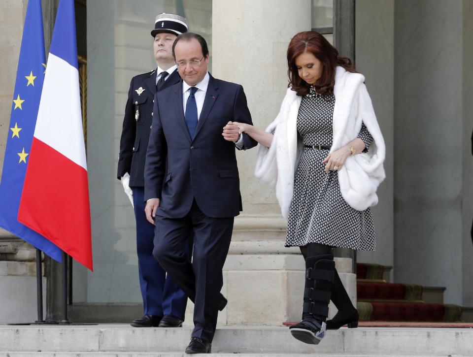 French President Francois Hollande, left, aids Argentine President Cristina Fernandez as she leaves after a press conference at the Elysee Palace in Paris, Wednesday, March 19, 2014. Fernandez met French counterpart and discussed ways to tackle her country's growing international debt. Fernandez injured her foot during her visit to Italy earlier this week. (AP Photo/Christophe Ena)