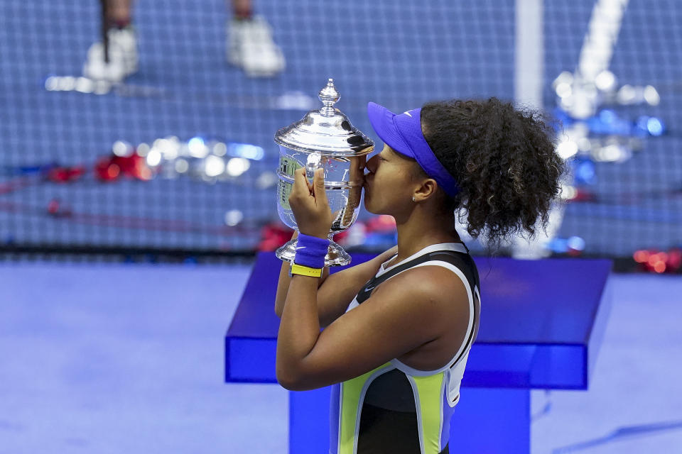 FILE - Naomi Osaka, of Japan, holds up the championship trophy after defeating Victoria Azarenka, of Belarus, in the women's singles final of the U.S. Open tennis championships in New York, in this Saturday, Sept. 12, 2020, file photo. The two singles champions at this year’s U.S. Open each will earn 35% less than in 2019, the last time the Grand Slam tennis tournament allowed spectators, while prize money for qualifying and the first three rounds of the main draw will rise as part of an overall increase. A year after banning fans entirely during the coronavirus pandemic and lowering prize money because of lost revenue, the U.S. Tennis Association announced Monday, Aug. 23, 2021, that it will be boosting total player compensation to a record $57.5 million, slightly more than the $57.2 million in 2019. (AP Photo/Seth Wenig, File)