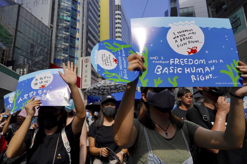 Protesters carrying placards march on a street in Hong Kong, Sunday, Sept. 15, 2019. Thousands of Hong Kong people chanted slogans and marched Sunday at a downtown shopping district in defiance of a police ban, with shops shuttered amid fears of renewed violence in the months-long protests for democratic reforms in the semi-autonomous Chinese territory. (AP Photo/Vincent Yu)